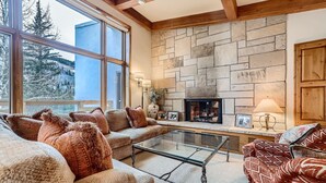A cozy living room with a stone fireplace, large windows, and comfortable seating. - Ski-in Condo w Vail Views near Gondola, TT5C (Vail)