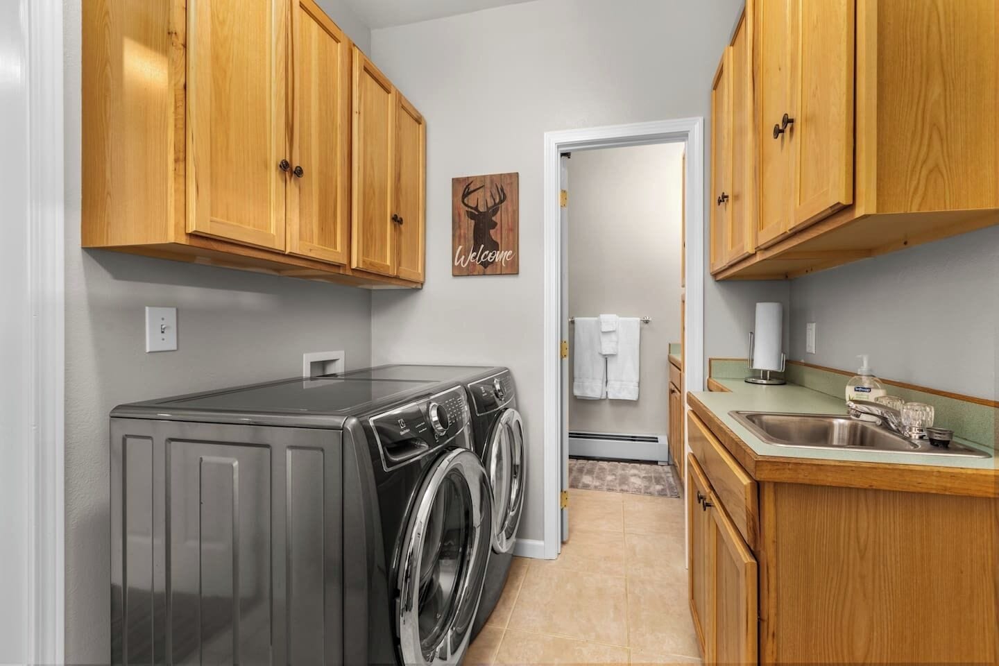 A compact laundry room with wooden cabinets, a washing machine, and a sink.