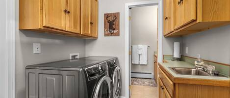 A compact laundry room with wooden cabinets, a washing machine, and a sink.