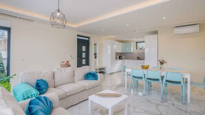 A modern living room with a sofa, coffee table, and dining area with chairs.