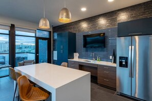 Una cucina moderna con una grande isola, mobili scuri, elettrodomestici in acciaio inossidabile e vista sulla città attraverso ampie finestre.