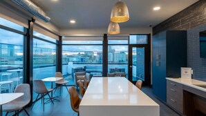 Cocina moderna con una isla grande, comedor con sillas y ventanas amplias con vistas a la ciudad.