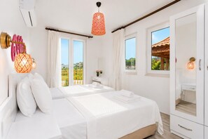 Quarto com cama grande, duas janelas, varanda e banheiro visível por uma porta aberta.
