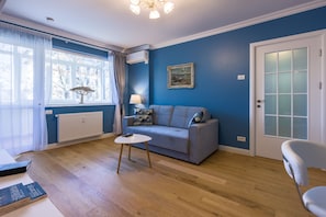 Un salon avec un mur bleu, un canapé gris, une table basse blanche et une chaise blanche.
