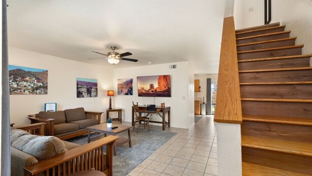 A living room with a sofa, a coffee table, a dining table, and chairs. There is a staircase to the right. - Spacious Williams Retreat near Grand Canyon (Williams)