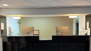 Un comptoir d’accueil au design moderne, un mur orné d’un motif derrière, et un sol texturé aux tons de bleu et de gris.