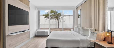 Un dormitorio moderno con una cama grande, televisor integrado y vistas al exterior.