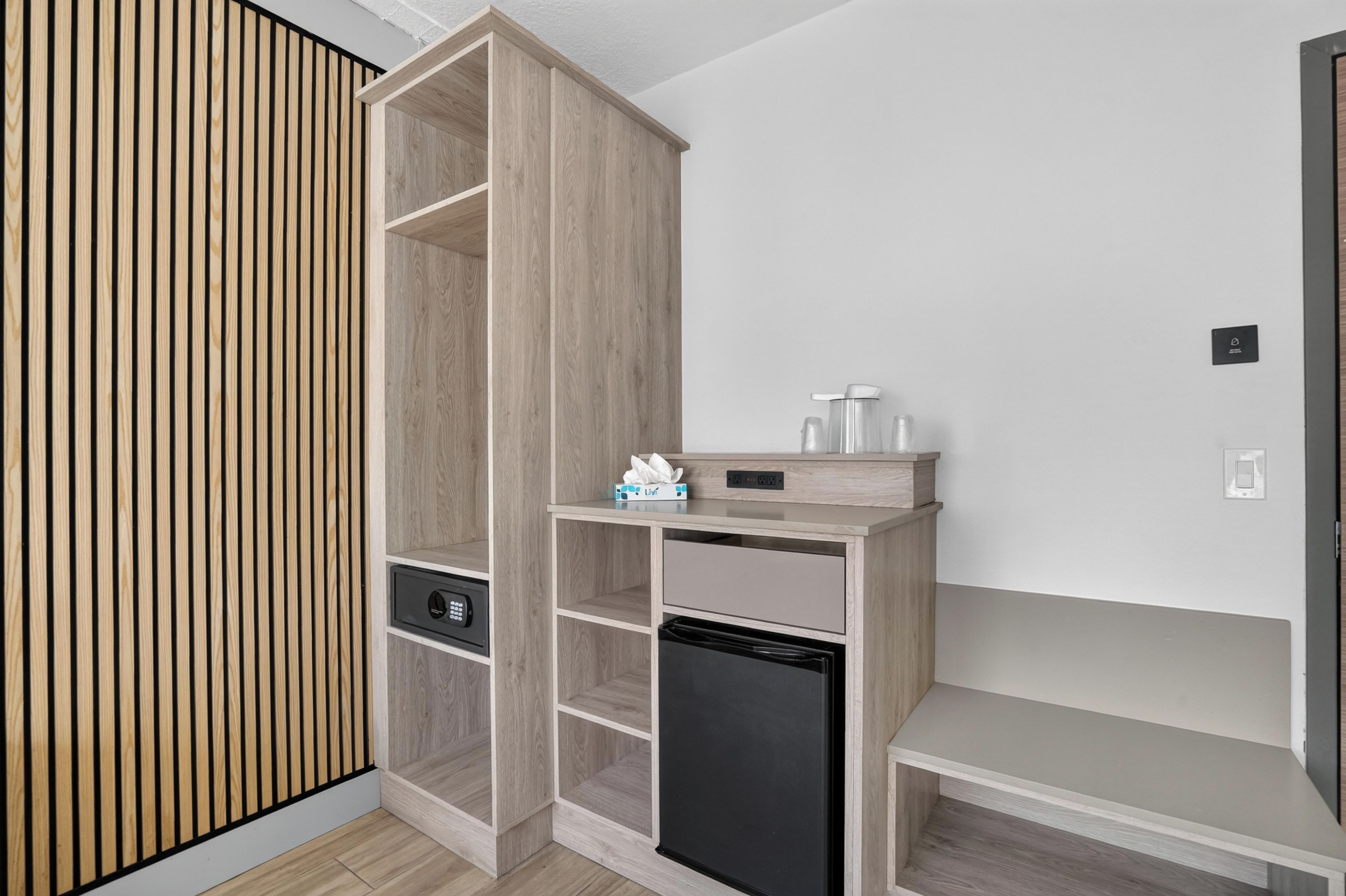 Une chambre moderne dotée d’une armoire intégrée, d’un petit coin cuisine et d’un banc.