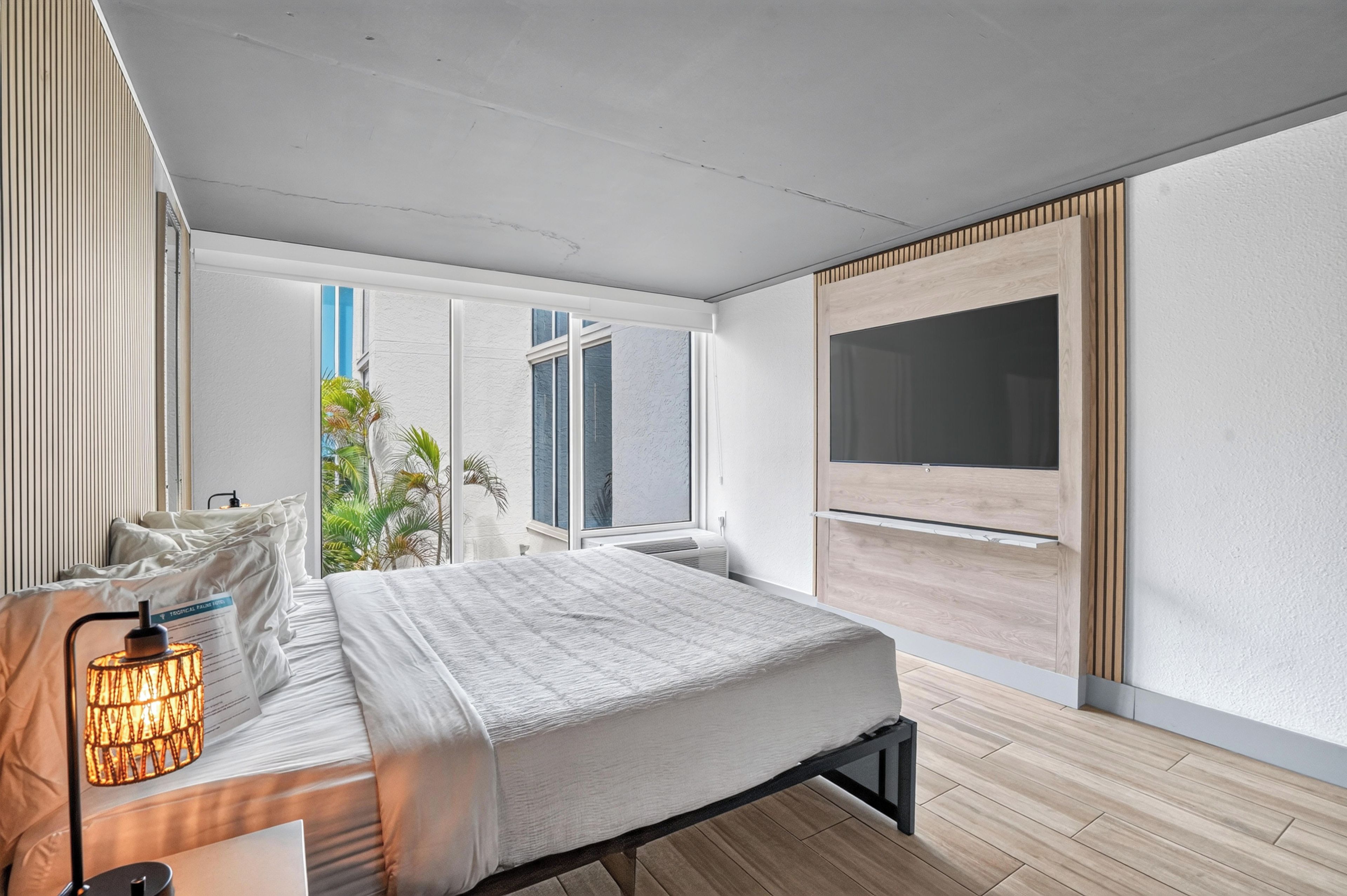 Une chambre à coucher moderne, avec un lit, une table de chevet, une lampe et une grande fenêtre donnant sur un beau paysage.