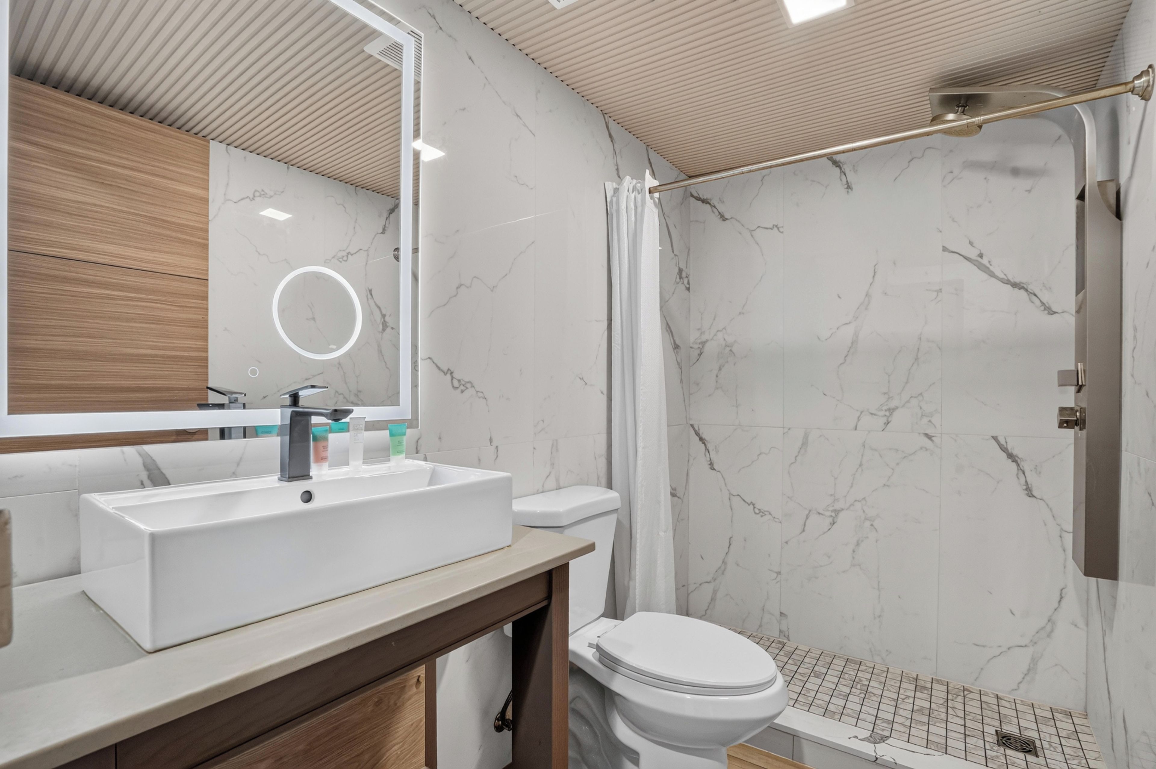 Une salle de bain moderne avec un grand miroir, un lavabo et un espace douche.