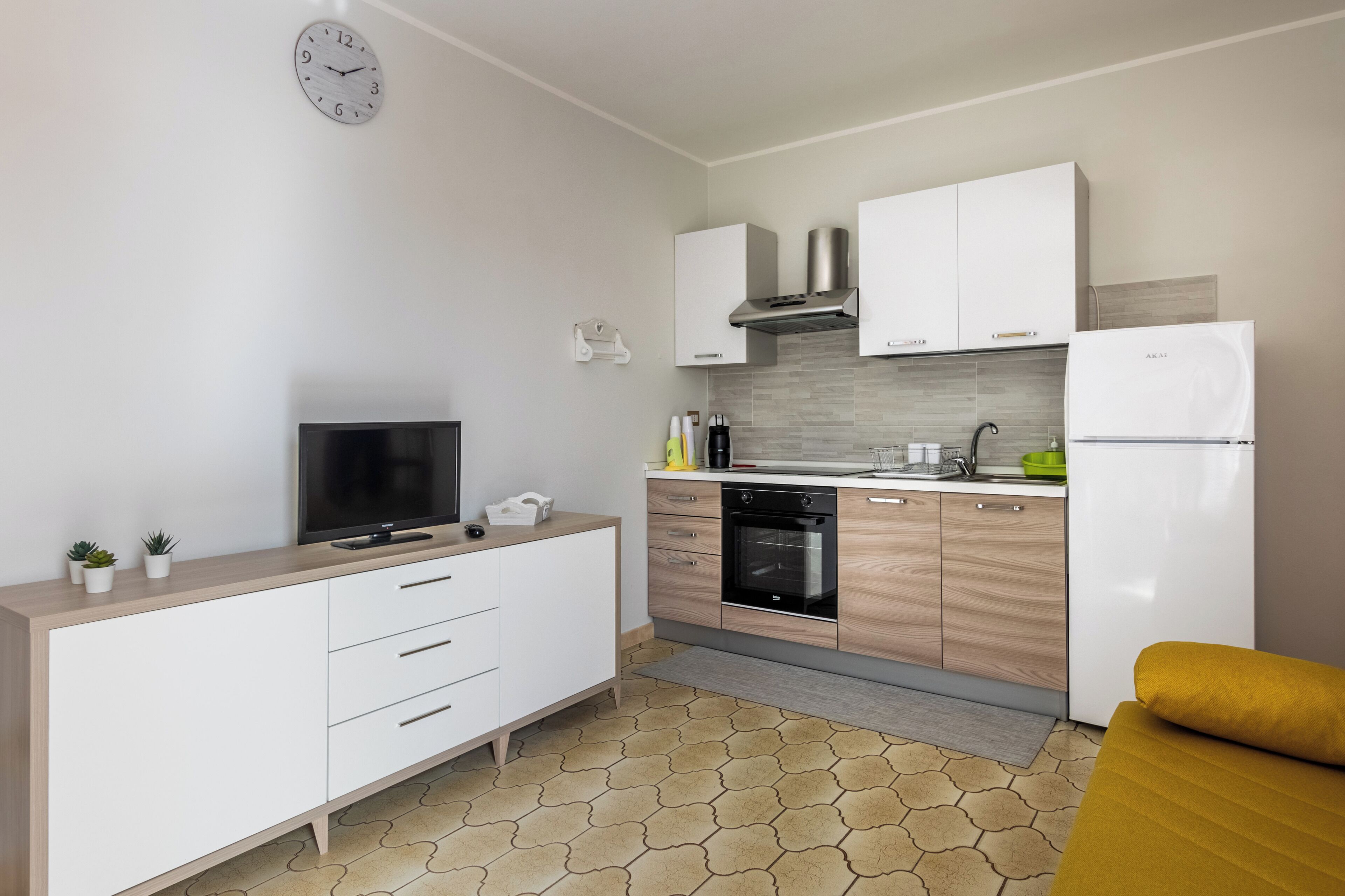 Una cucina moderna con mobili bianchi, forno integrato e frigorifero.