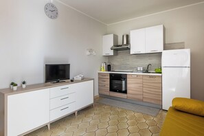 A modern kitchen with white cabinetry, a built-in oven, and a refrigerator.