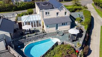 A large house with a swimming pool, a covered patio, and a stone wall surrounding the pool.
