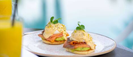 Zwei Eggs Benedict Sandwiches auf einem Teller, im Vordergrund ein Glas Orangensaft.