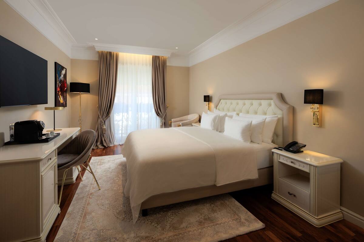 Un dormitorio de hotel con una cama grande, mesitas de noche, un escritorio y un televisor.