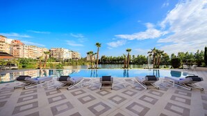 A poolside area with lounge chairs and a clear view of a lake and buildings in the background.