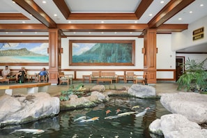 Relax by the serene koi pond surrounded by lush greenery and large rocks.