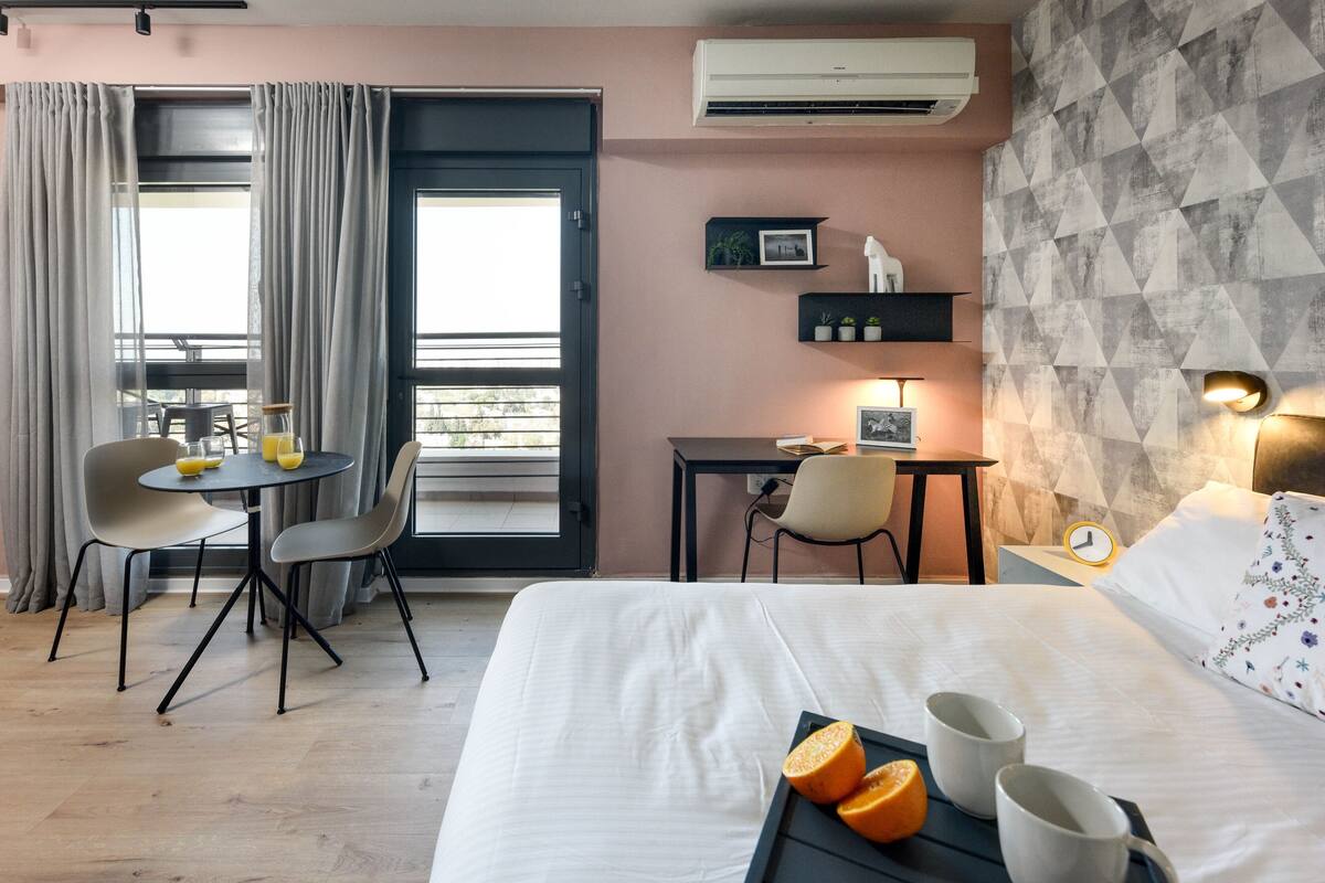 Habitación de hotel con cama, bandeja de desayuno, mesa de comedor, sillas y escritorio.
