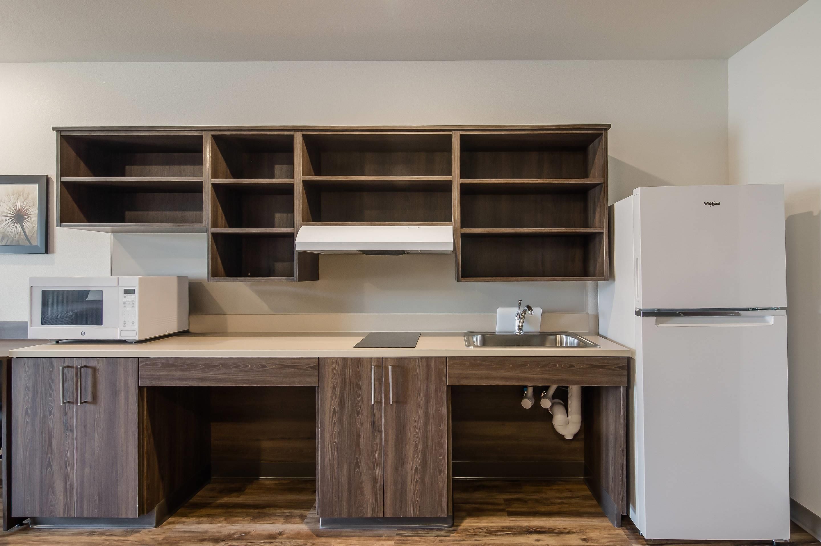 A kitchen with a built-in microwave, a refrigerator, and wooden cabinets.
