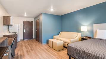 A hotel room with a bed, a sofa, a desk, and a door.