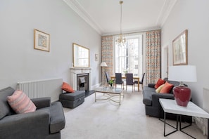 A living room with a fireplace, two sofas, a coffee table, and a dining area with chairs.