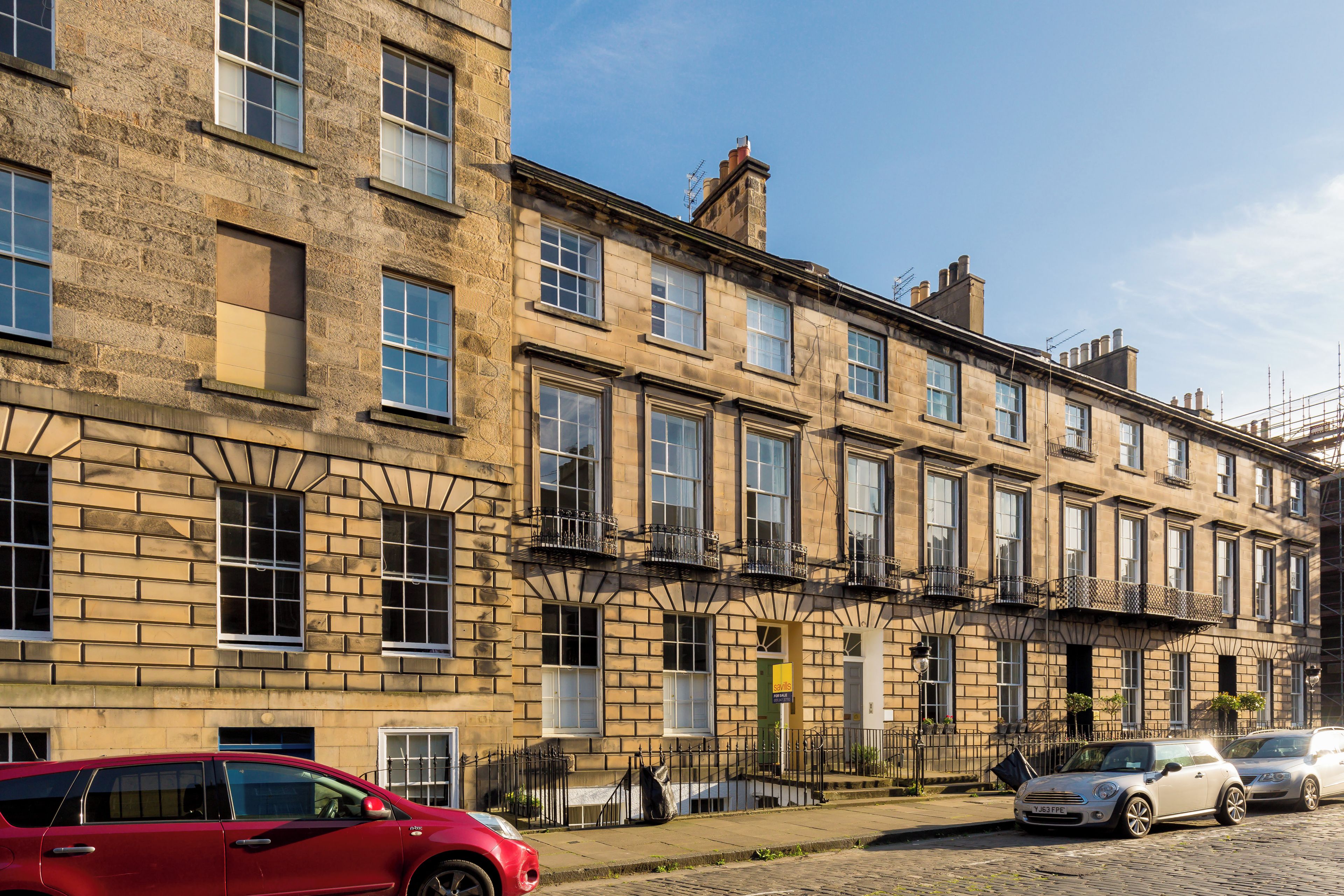 A row of terraced houses with a red car parked in front.