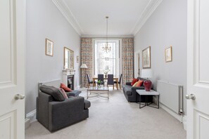 A spacious living room with a fireplace, a dining area, and a view of the city through large windows.