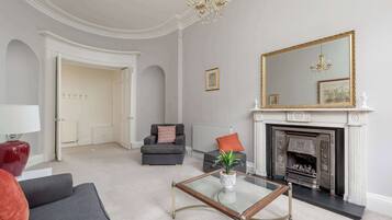 A living room with a fireplace, a large mirror, and a chandelier.