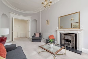 A living room with a fireplace, a large mirror, and a chandelier.
