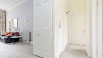 Une pièce avec un canapé gris, une lampe rouge et une porte blanche.
