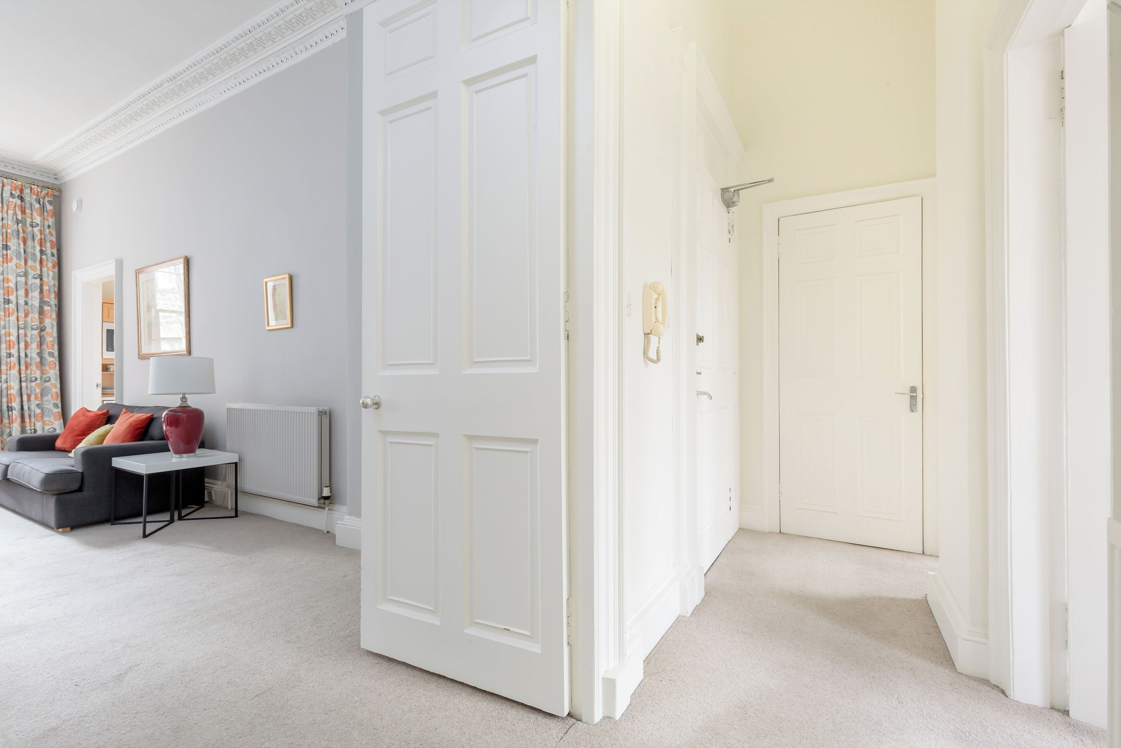 A room with a grey sofa, a red lamp, and a white door.