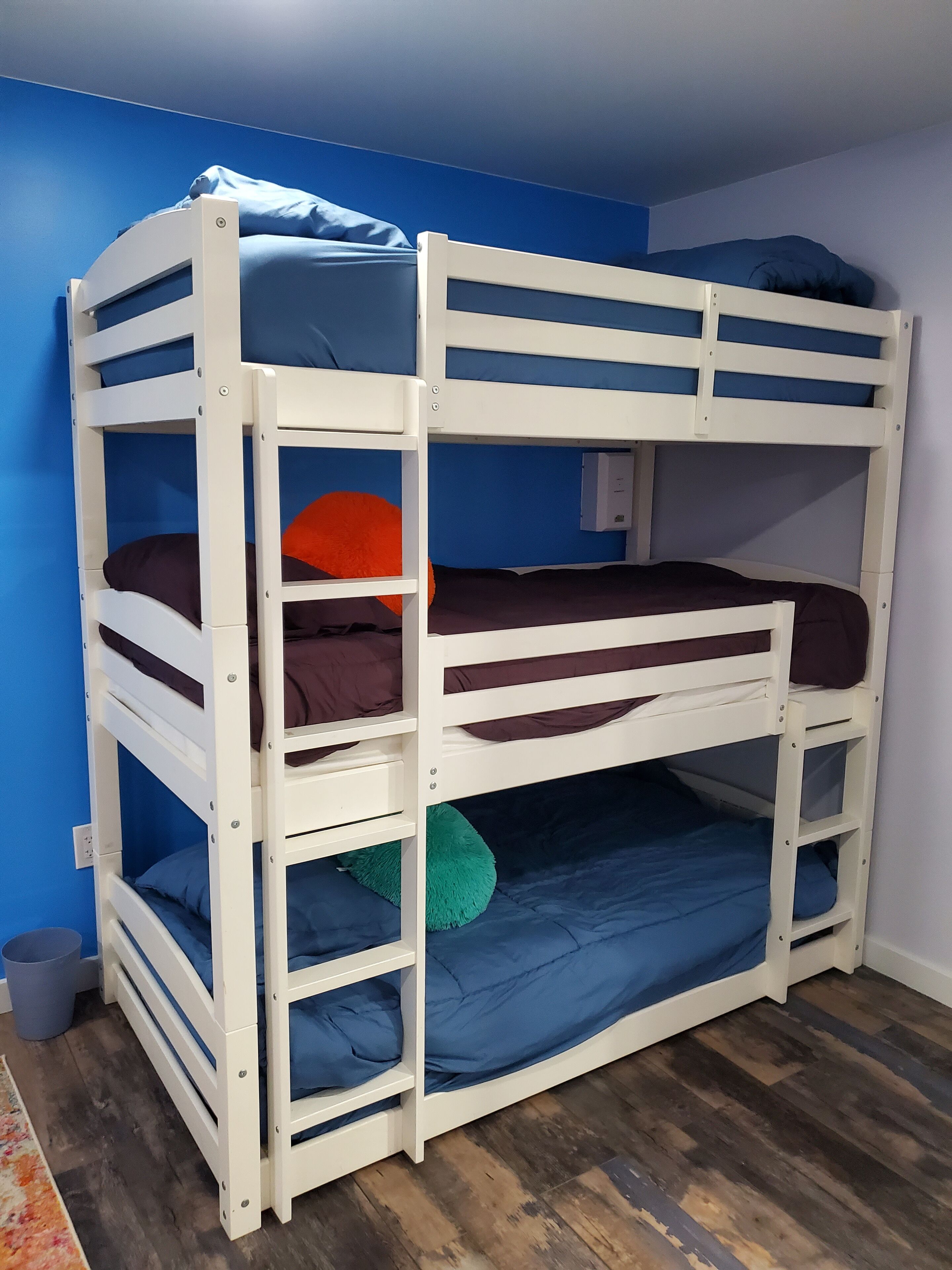 A bunk bed with three levels, each with a mattress and pillows.