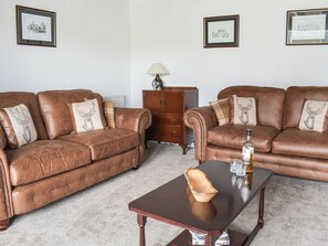 A living room with two brown leather sofas, a wooden coffee table, and a small cabinet.