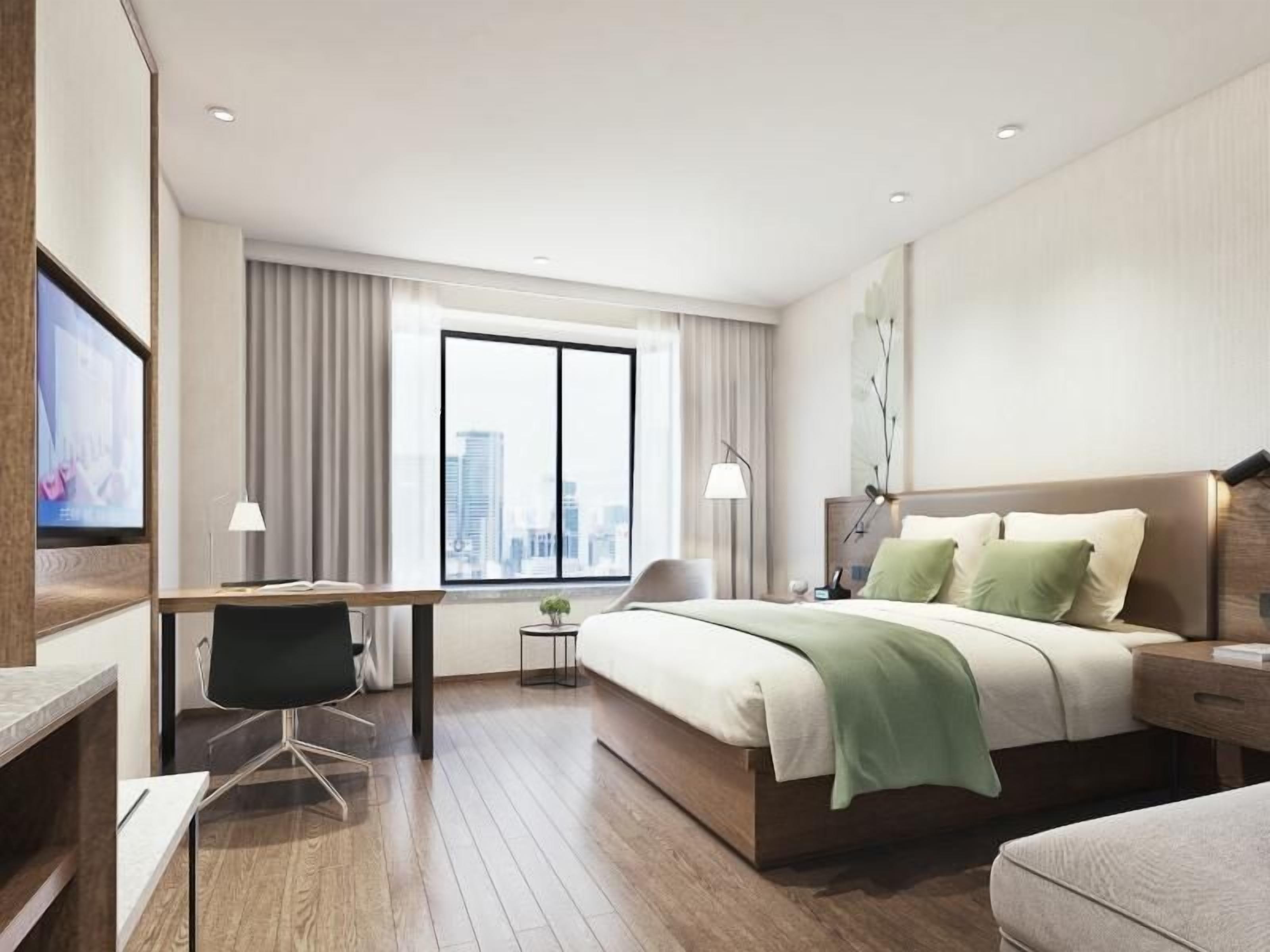 Una habitación de hotel moderna con una cama grande, un escritorio, una silla y un televisor.