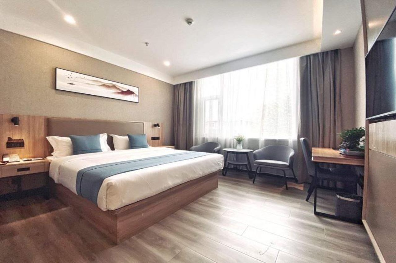 A modern hotel room with a large bed, bedside tables, a desk, and a chair.