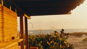 A beachside view with a wooden structure, beach chairs, and umbrellas. - Terrestre, a Member of Design Hotels (Villa de Tututepec de Melchor Ocampo)