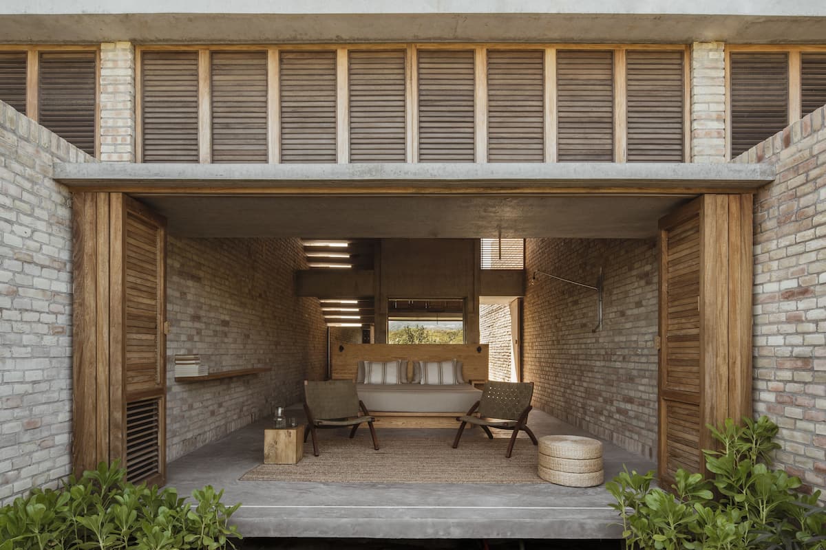 A modern outdoor seating area with a bench, two chairs, and a small table.