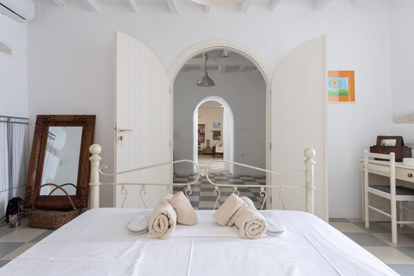 Classic design meets functionality in this well-appointed bedroom with a large bed, desk, and wicker accents.