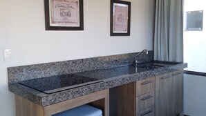 Une cuisine dotée de plans de travail en granit, de meubles en bois, d’un four à micro-ondes encastré et de deux certificats encadrés accrochés au mur.