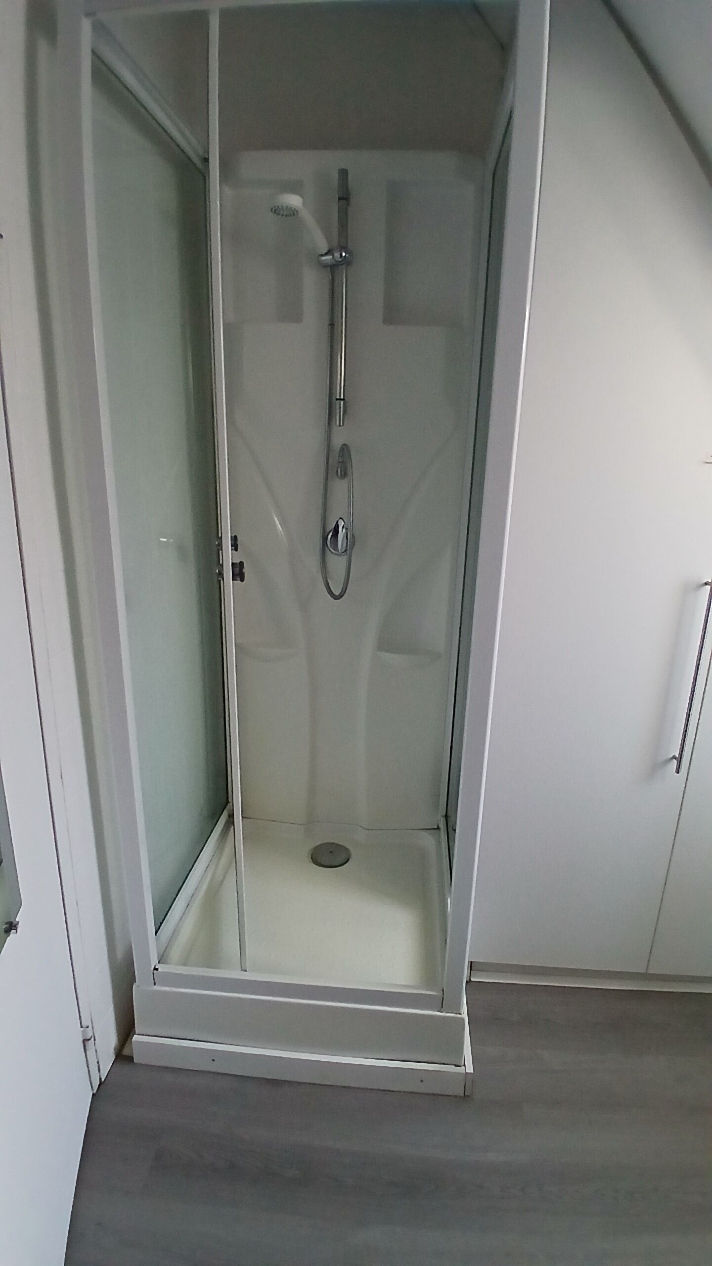 A glass-enclosed shower area with a showerhead and control panel.