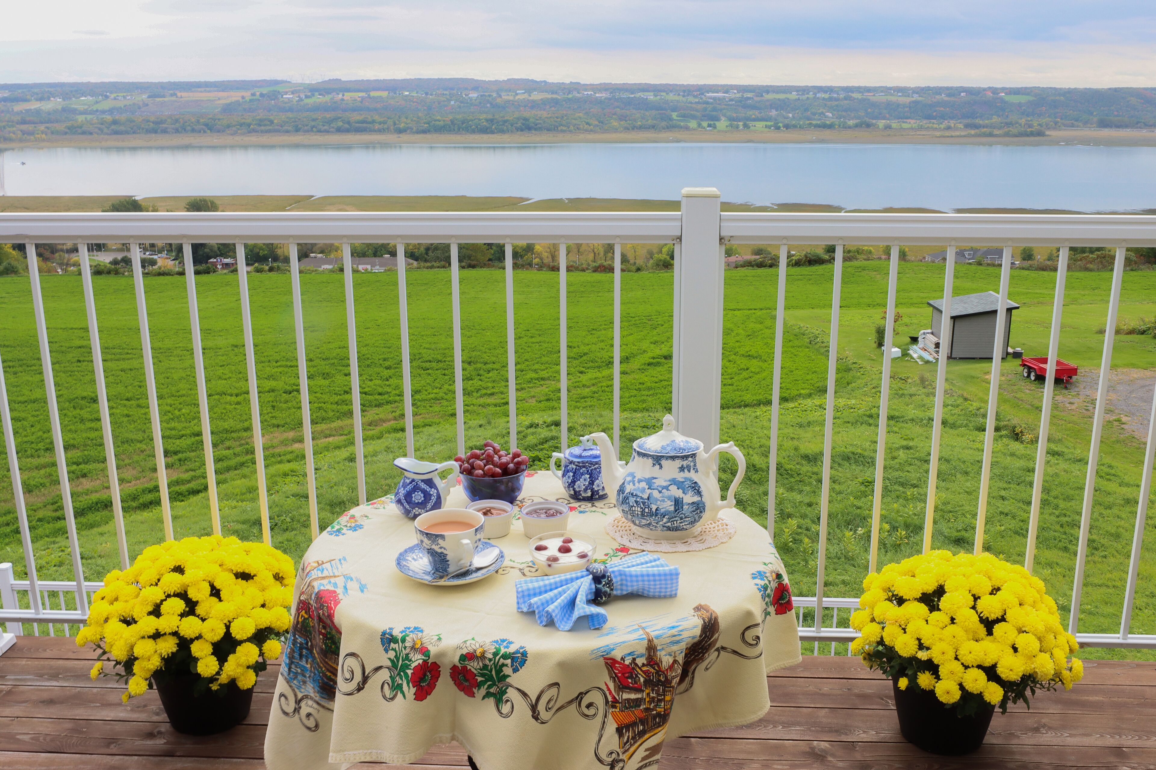 Une table dressée avec du thé et des en-cas sur un balcon donnant sur un lac.