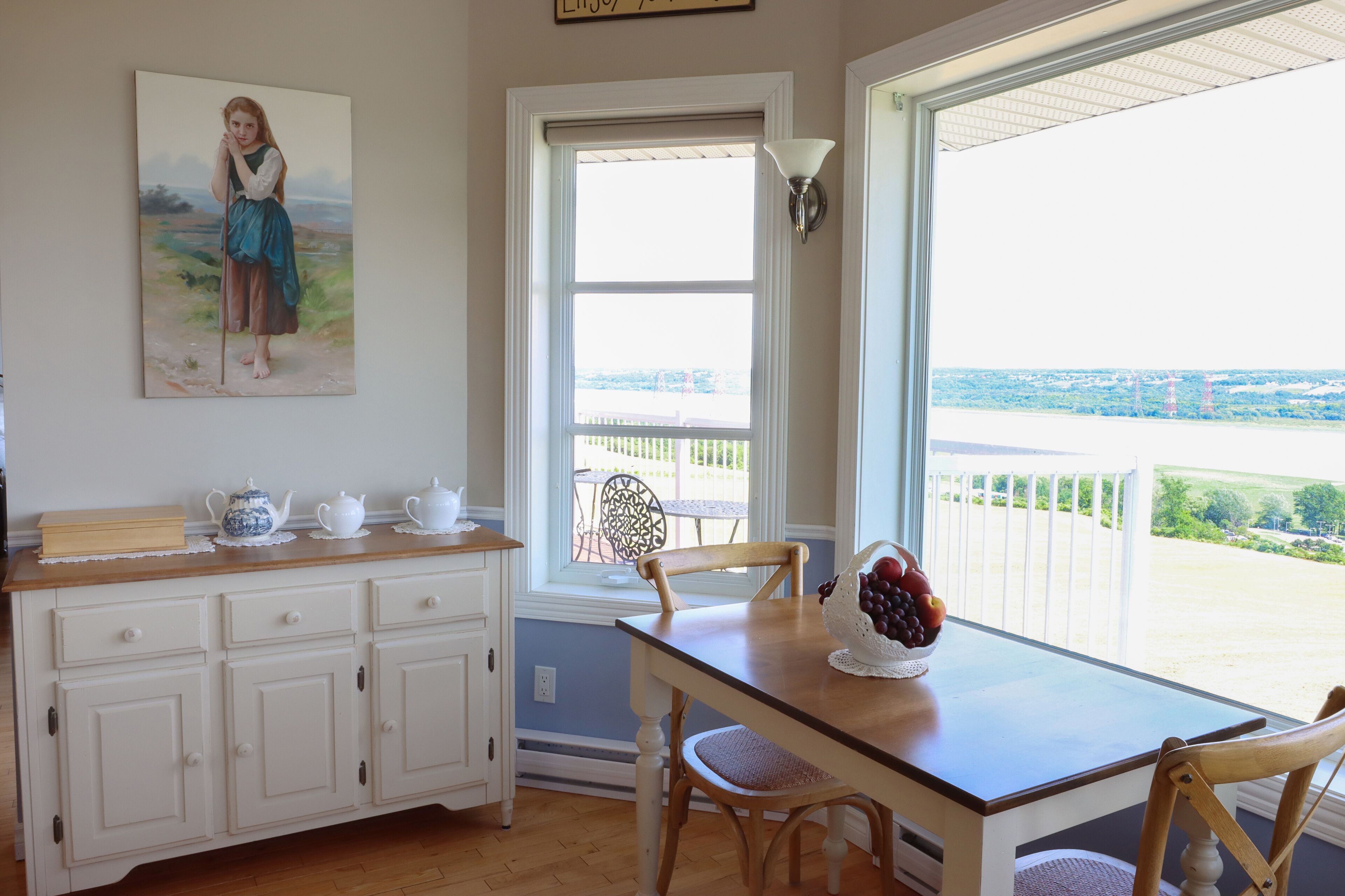 Un comedor con mesa, sillas, vistas al exterior, una ventana y un cuadro en la pared.