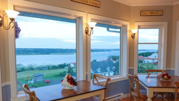 Un comedor con una mesa dispuesta para cuatro personas, vista a un lago y un letrero que dice "Bon appétit!"