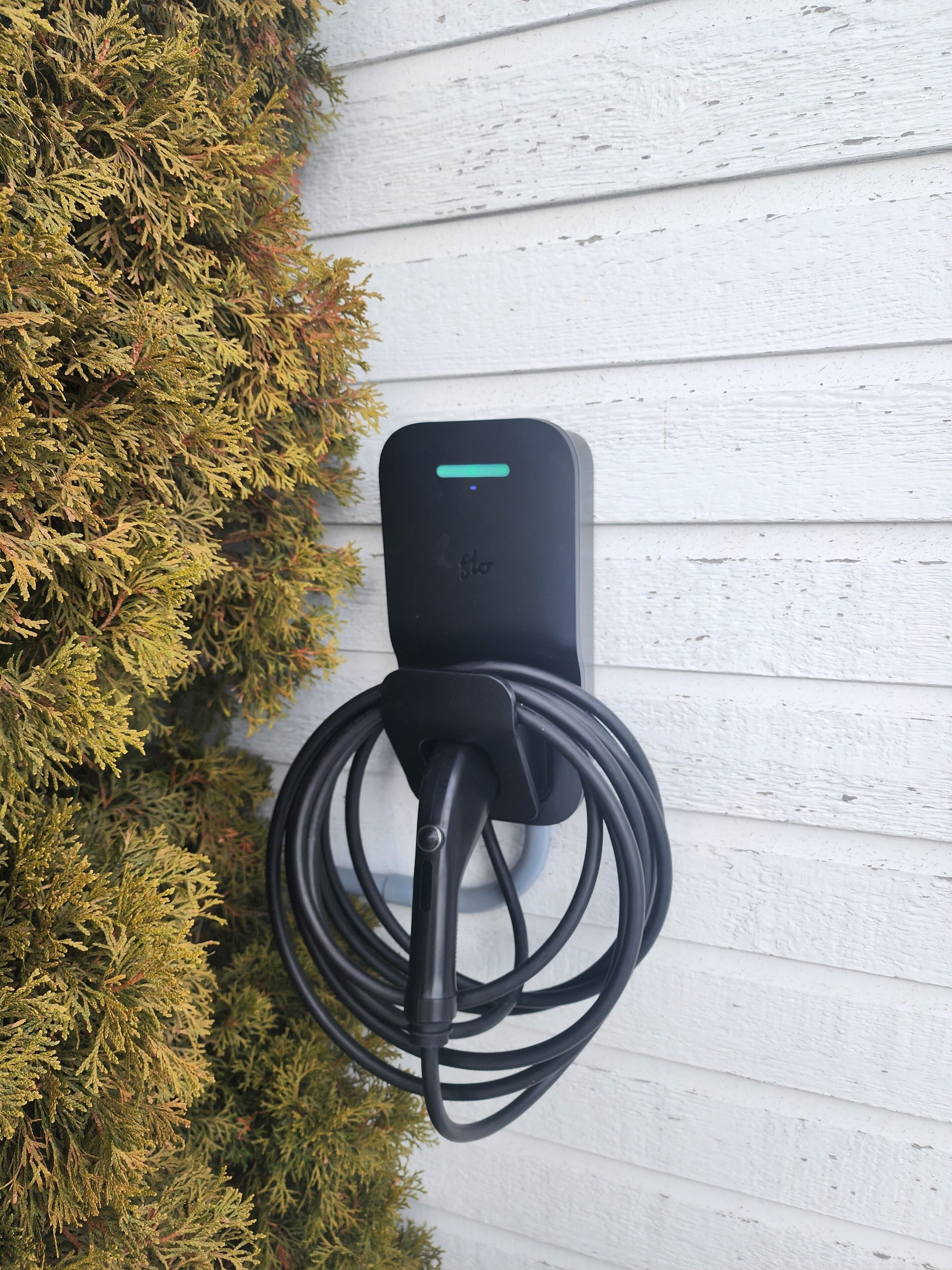 An electric vehicle charging station mounted on a white wooden wall.