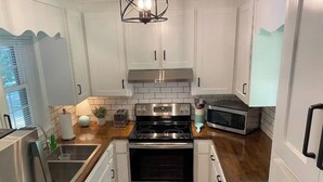 A modern kitchen with white cabinets, stainless steel appliances, and a wooden countertop. - Convenient 3 Bedroom / 2 Bath house (Gainesville)