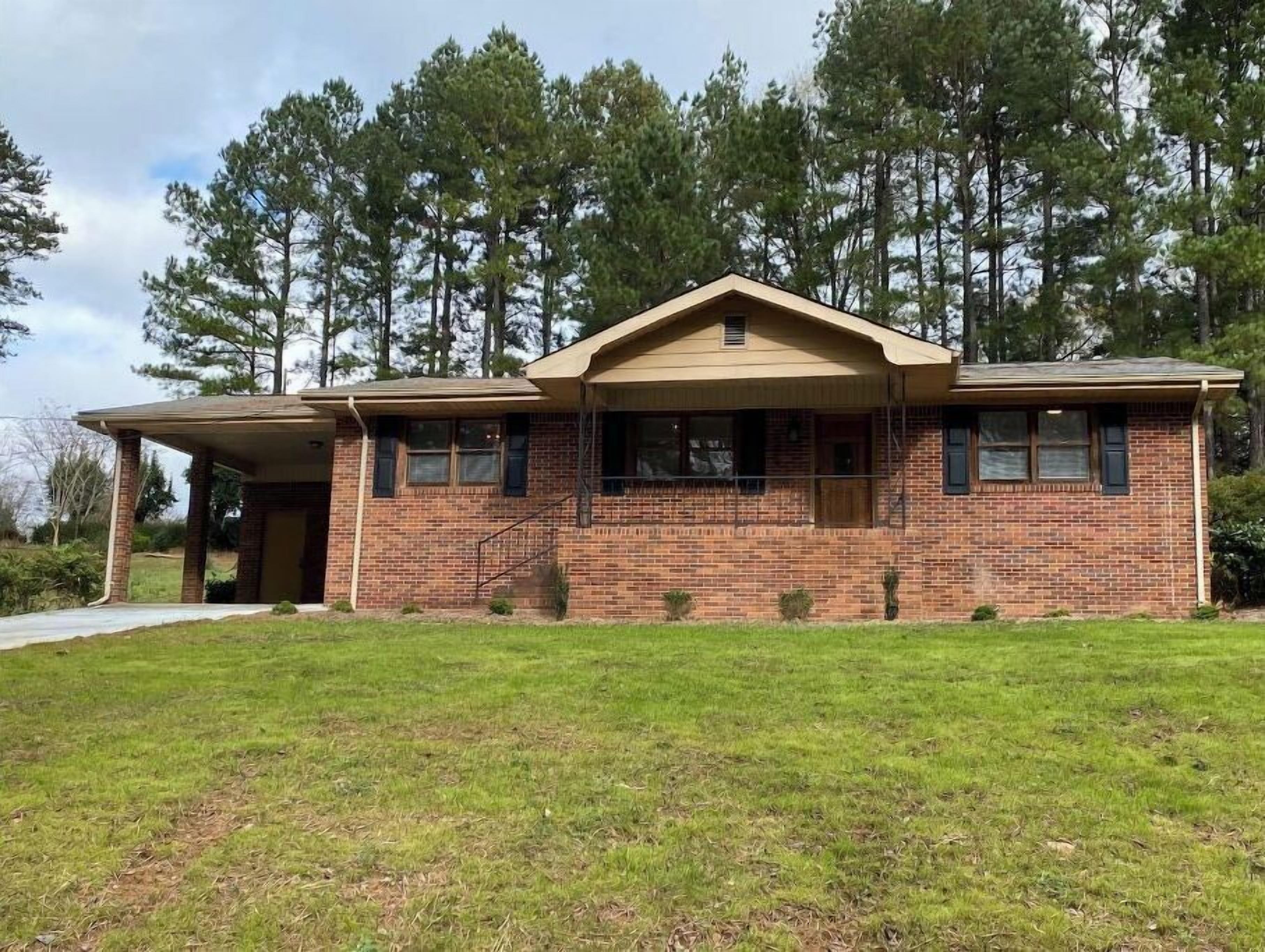 A single-story brick house with a gabled roof and a covered porch.