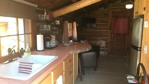 Une cuisine rustique avec des armoires en bois, un grand évier et un réfrigérateur.