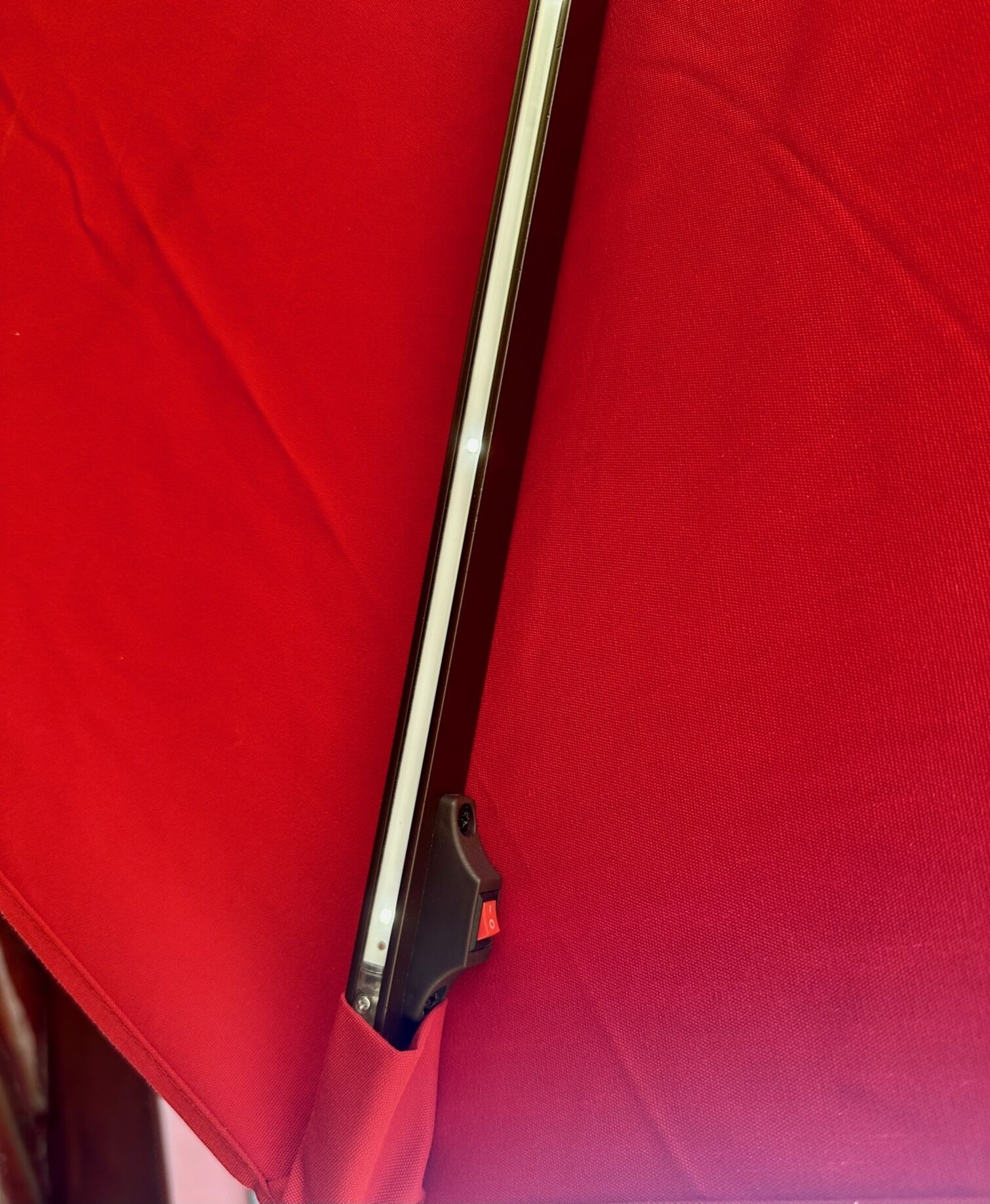 Una silla roja con estructura metálica y un apoyabrazos negro.