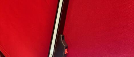 Una silla roja con estructura metálica y un apoyabrazos negro.