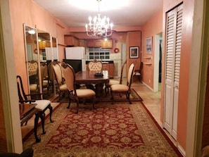 A dining area with a chandelier, a red patterned rug, and wooden furniture.